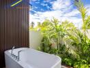 Modern bathroom with an outdoor feel featuring a freestanding bathtub and lush greenery.