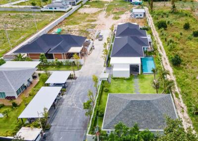 Aerial view of residential property complex with multiple houses and a swimming pool