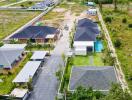 Aerial view of residential property complex with multiple houses and a swimming pool