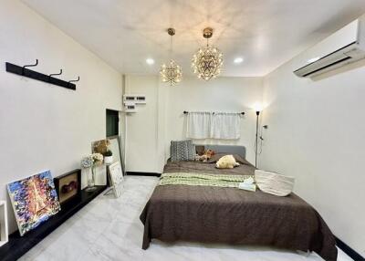 Modern bedroom with double bed, wall hooks, hanging lights, and air conditioning