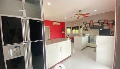 Modern kitchen with large refrigerator, island counter, and ceiling fan