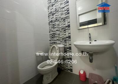 Modern bathroom with a tiled wall, a toilet, and a sink.