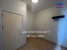 Empty bedroom with wooden floor and door, lit by ceiling light.