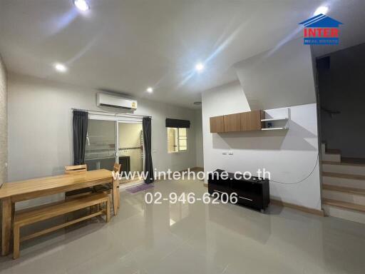 Modern living room with dining area, air conditioning, and staircase