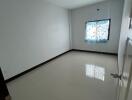 Empty bedroom with tiled floors and a large window with curtains