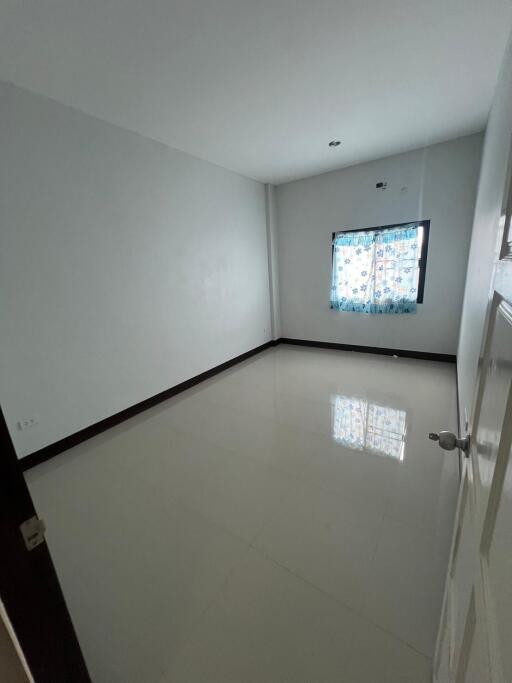 Empty bedroom with tiled floors and a large window with curtains