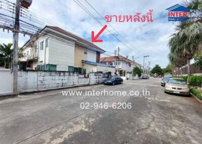 Street view of residential buildings with cars parked along the road