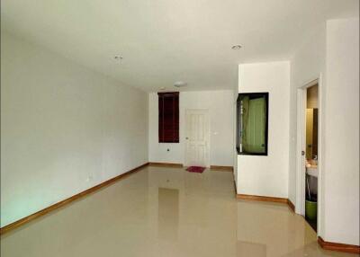 Spacious living room with tile flooring and a door leading to another room