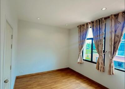 Bright empty bedroom with wooden flooring and large windows