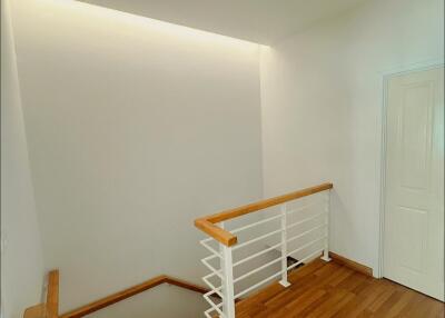 Modern indoor staircase with wooden steps and white handrail