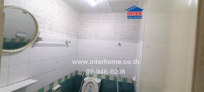 Bathroom with wall-mounted mirror, toilet, and tiled walls