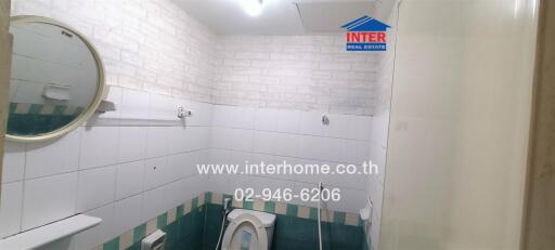 Bathroom with wall-mounted mirror, toilet, and tiled walls