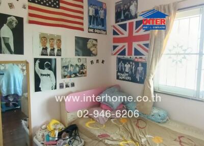 Small bedroom with posters on the wall and a window