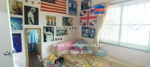 Small bedroom with posters on the wall and a window