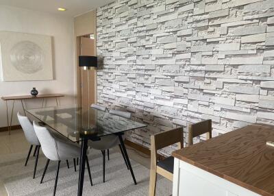 Contemporary-styled dining room with brick accent wall and glass table