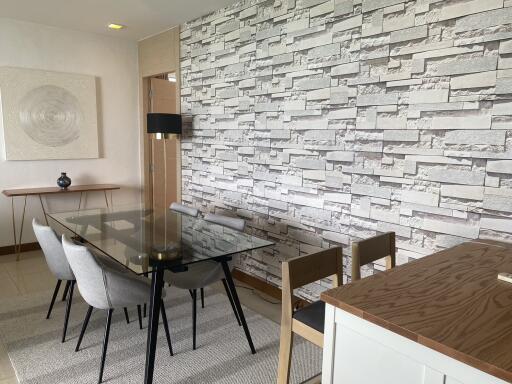 Contemporary-styled dining room with brick accent wall and glass table