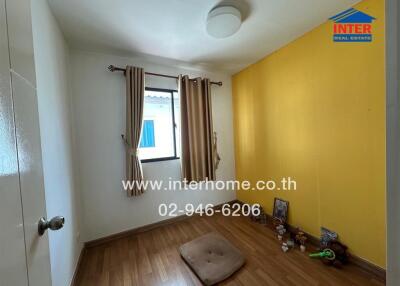 Small bedroom with wooden flooring and yellow accent wall