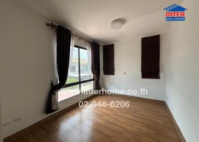 Empty bedroom with wooden floors and large window