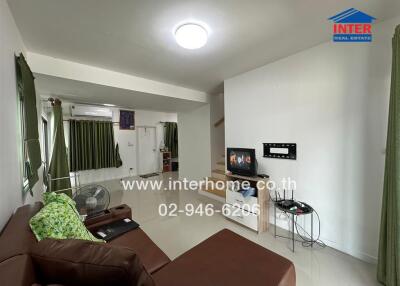 Living room with brown leather sofa, TV, and green curtains