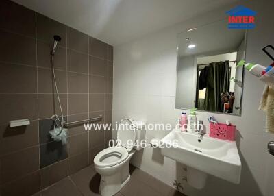 Modern bathroom with tiled walls, sink, and toilet