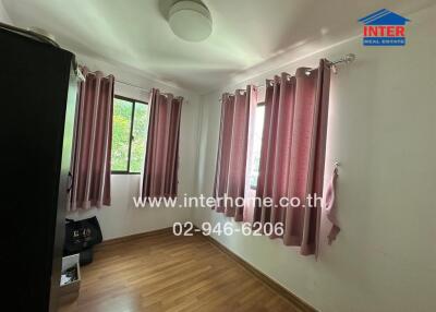 Small bedroom with wooden flooring, pink curtains, and large windows