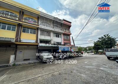 Street view of a commercial building with several floors and parked vehicles