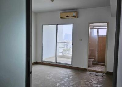 A bedroom with sliding doors, an air conditioning unit, balcony access, and an attached bathroom