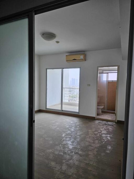 A bedroom with sliding doors, an air conditioning unit, balcony access, and an attached bathroom