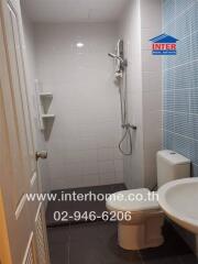 Modern bathroom with shower, toilet, and sink featuring tiled walls and floor.