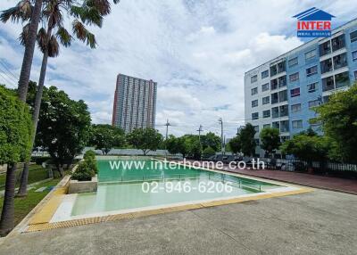 Outdoor view of pool area with adjacent buildings and greenery