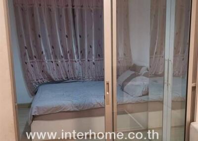 Bedroom with bed and curtains visible through a glass sliding door