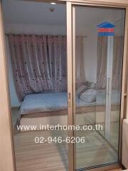 Bedroom with bed and curtains visible through a glass sliding door