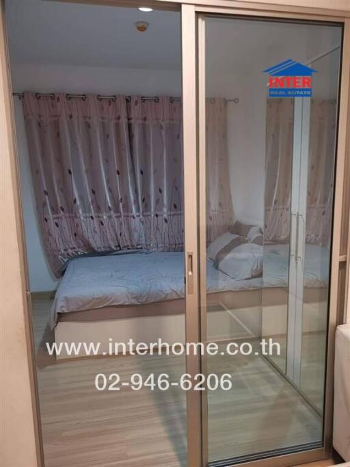 Bedroom with bed and curtains visible through a glass sliding door