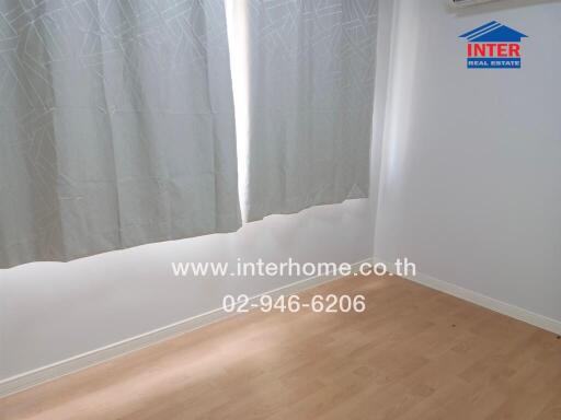 Empty bedroom with light-coloured curtains and wooden floor