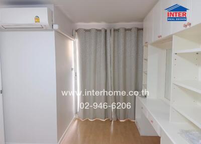 Bedroom with built-in shelves, air conditioner, and window with curtains