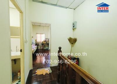 Hallway with stair railing and view of adjacent rooms