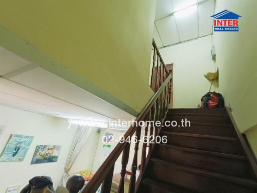 Dimly lit staircase near a living area with wall decorations and overhead lighting