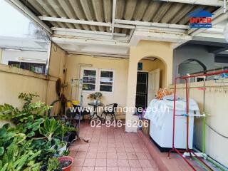 Covered patio area with plants and laundry equipment