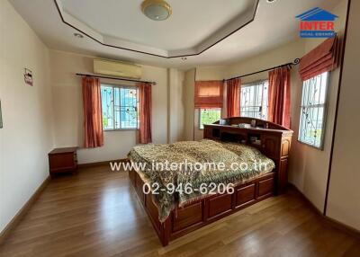 Spacious bedroom with sizable windows and a wooden bedframe