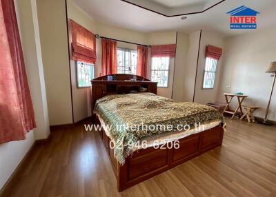 Spacious bedroom with wooden flooring and large windows