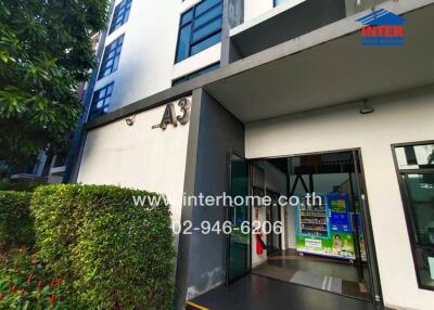 Entrance of a residential building with greenery and vending machines