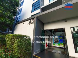 Entrance of a residential building with greenery and vending machines