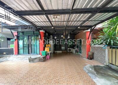 Spacious covered outdoor lounge with tiled floor, seating area, and greenery