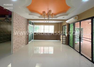 Spacious living room with tiled flooring, ceiling chandelier, and large windows