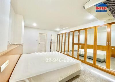 Spacious bedroom with large mirrors and wardrobe