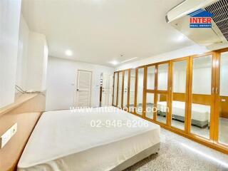 Spacious bedroom with large mirrors and wardrobe