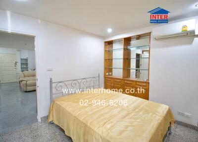 Bedroom with metal bed frame, beige bedding, and built-in wooden cabinetry.