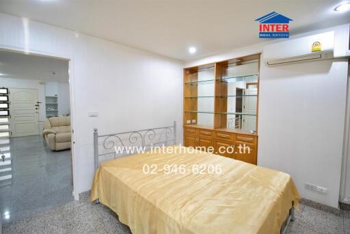 Bedroom with metal bed frame, beige bedding, and built-in wooden cabinetry.