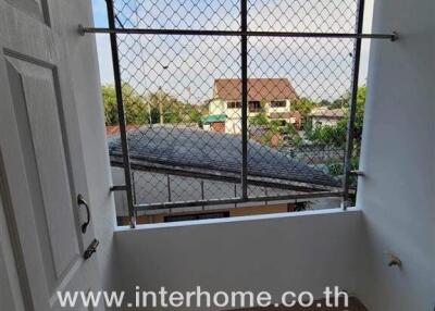 Small enclosed balcony with metal bars and a view of neighboring buildings