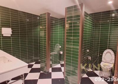 Spacious bathroom with green tiled walls and black and white checkered floor